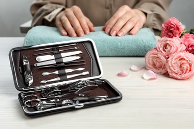 Woman at white wooden table, focus on case with manicure set