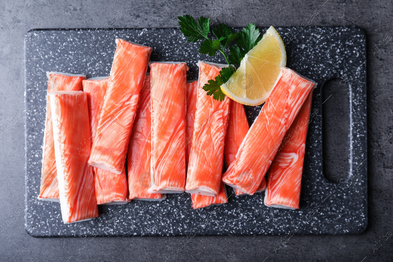 Photo of Fresh crab sticks with lemon on grey table, top view