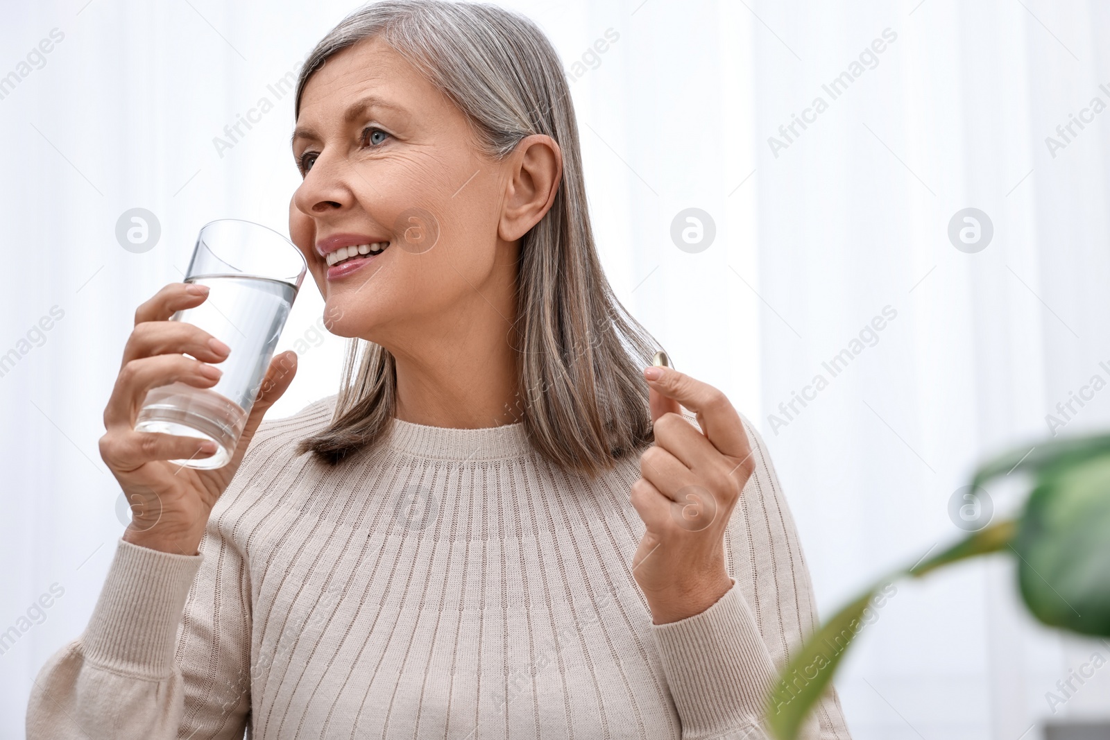 Photo of Beautiful woman taking vitamin pill at home