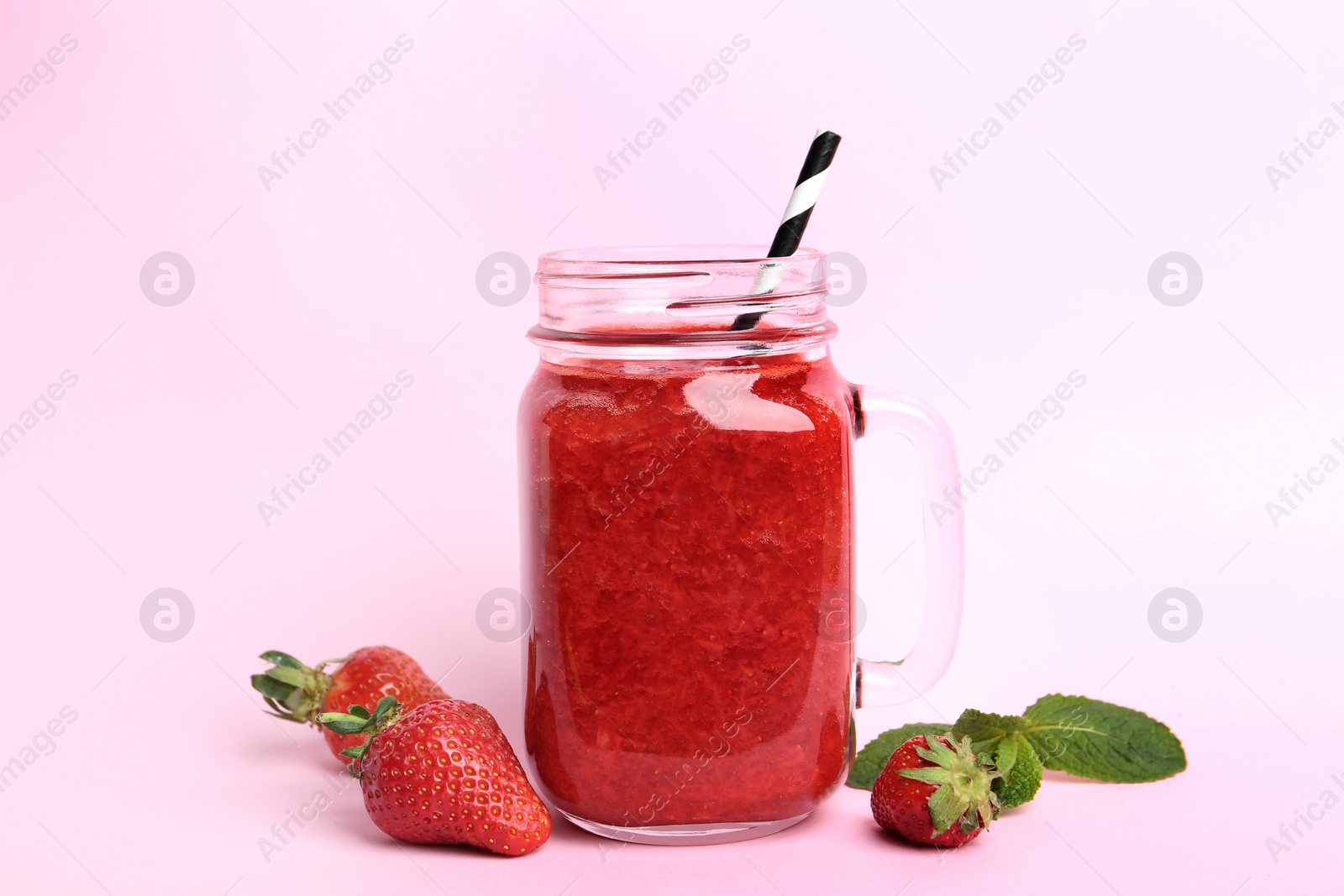 Photo of Tasty strawberry smoothie in mason jar on pink background