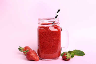 Photo of Tasty strawberry smoothie in mason jar on pink background