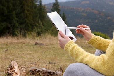 Photo of Woman drawing with graphic tablet in mountains, closeup