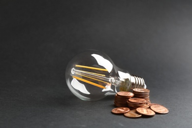 Many coins and light bulb on black background