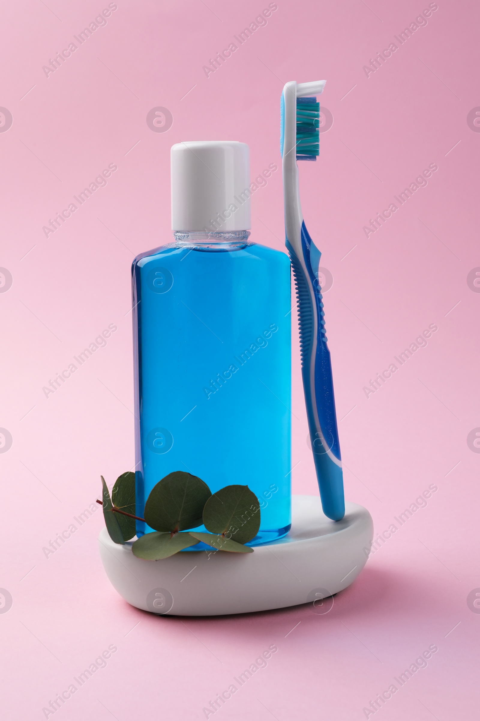 Photo of Fresh mouthwash in bottle and toothbrush on pink background