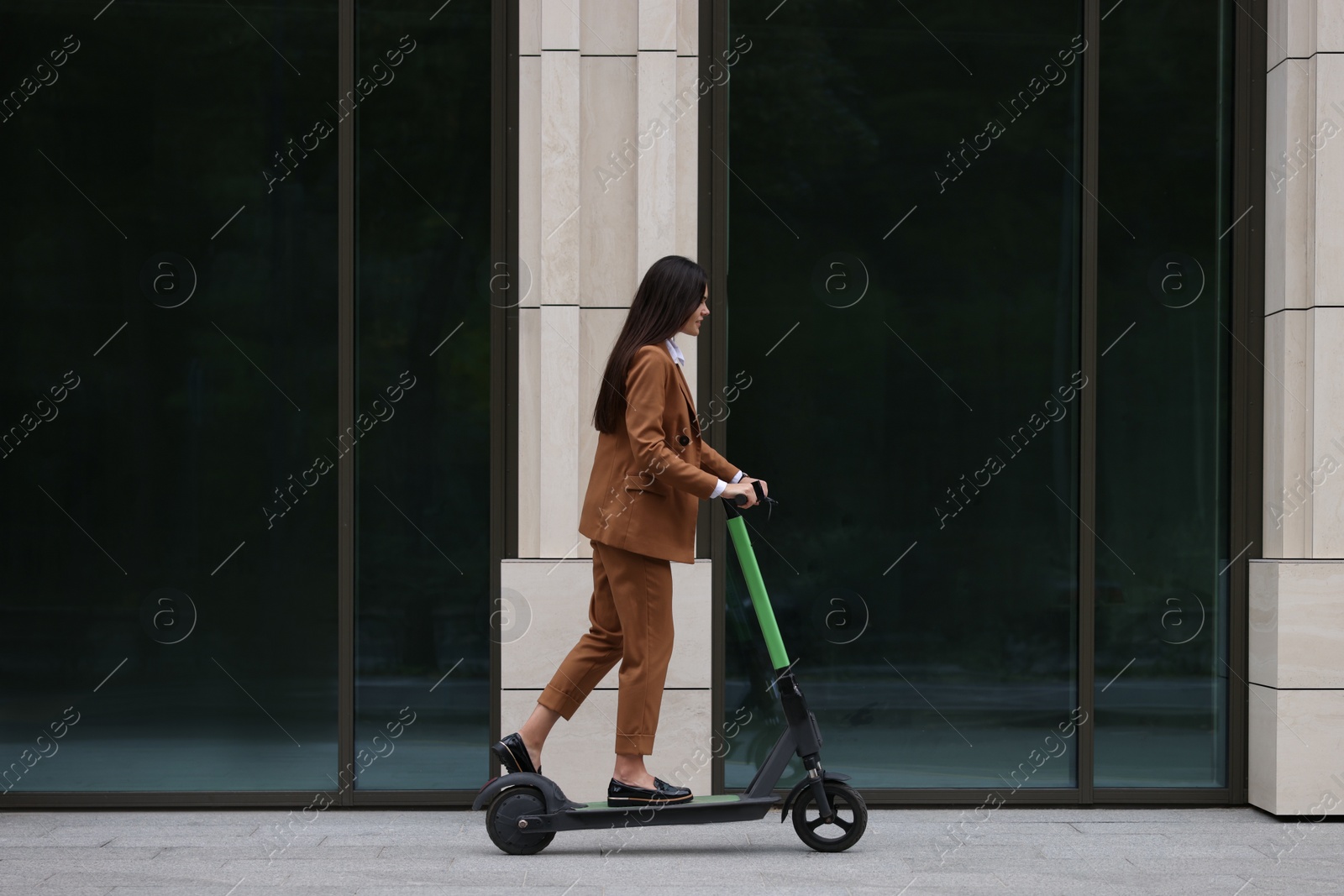 Photo of Businesswoman riding electric kick scooter on city street