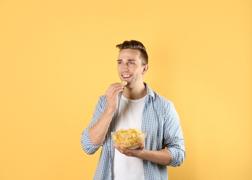 Photo of Man eating potato chips on color background