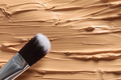 Photo of Skin foundation and makeup brush as background, closeup