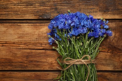 Bouquet of beautiful cornflowers on wooden table, top view. Space for text