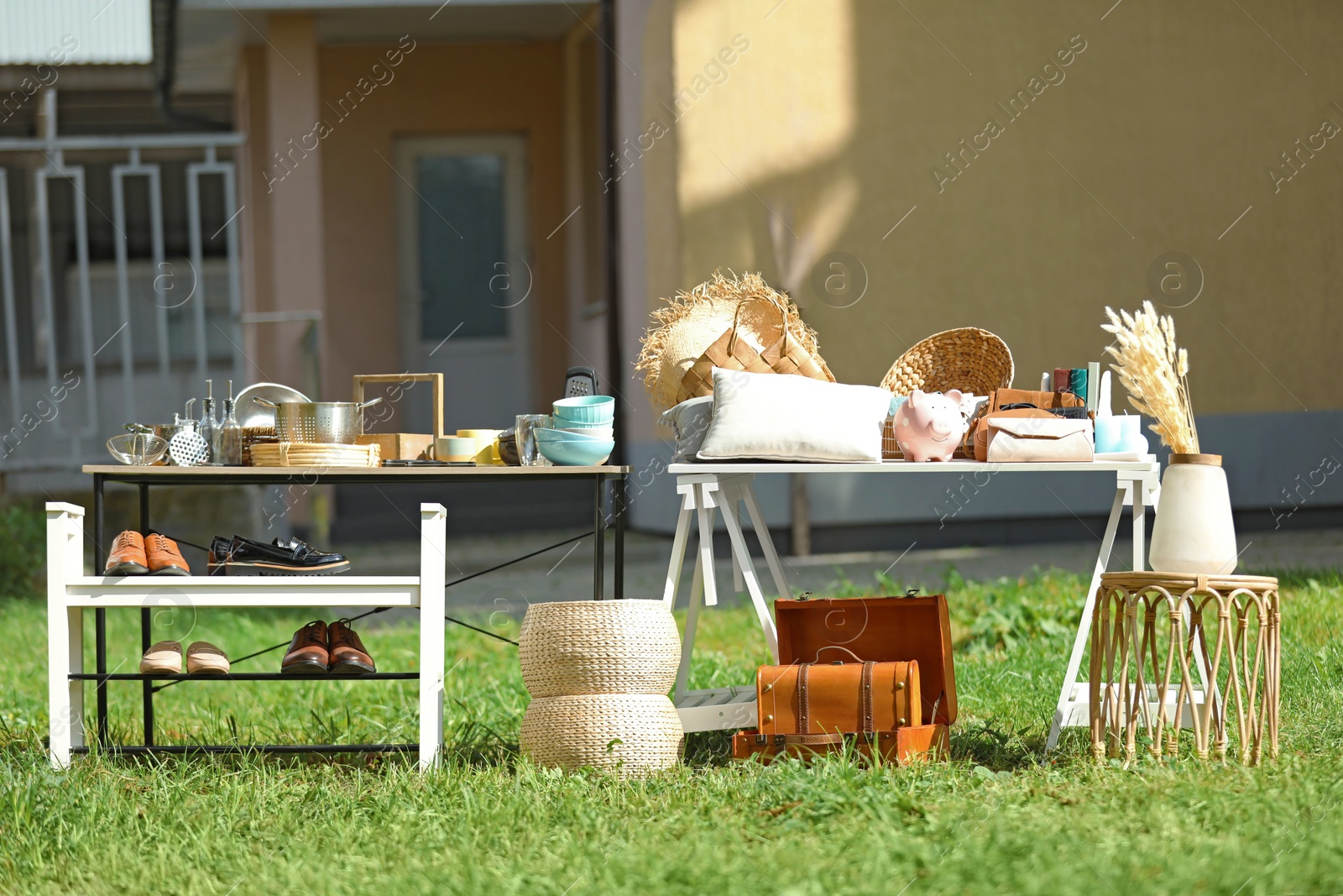 Photo of Small tables with many different items on garage sale in yard