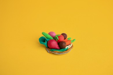 Photo of Different plasticine vegetables on yellow background. Children's handmade ideas