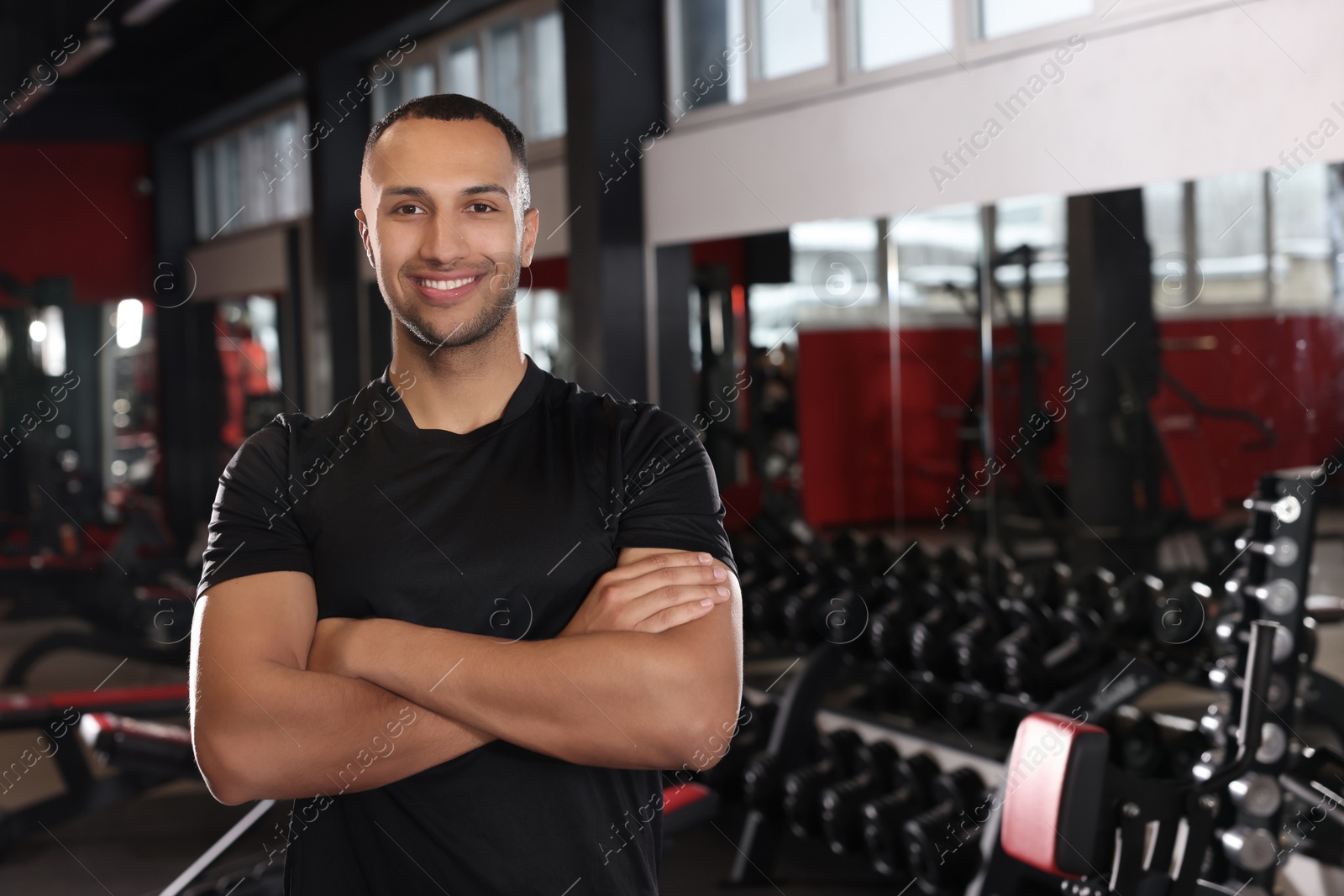 Photo of Happy trainer in modern gym, space for text