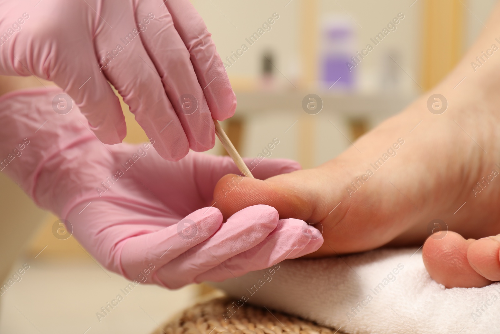 Photo of Professional pedicurist working with client`s toenails in beauty salon, closeup