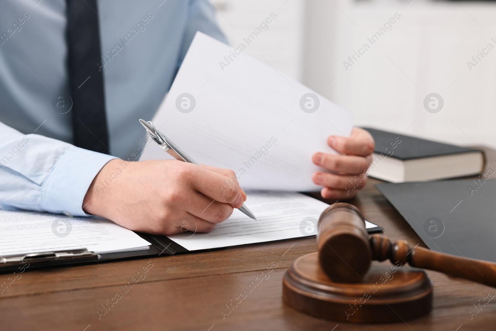 Photo of Lawyer working with documents at wooden table in office, closeup