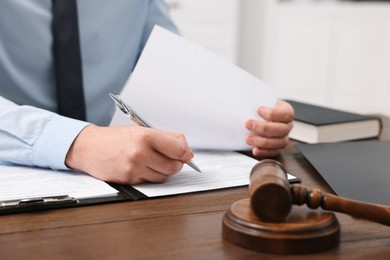 Lawyer working with documents at wooden table in office, closeup