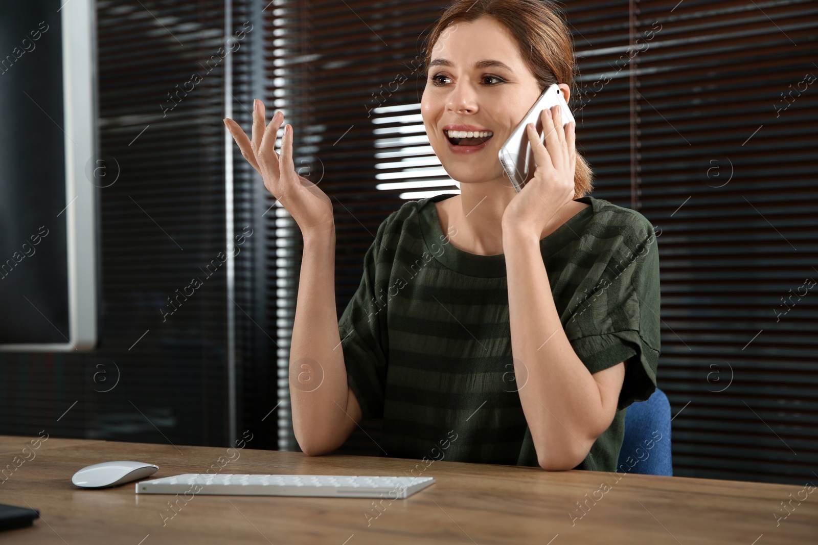 Photo of Female technical support operator talking on mobile phone at workplace