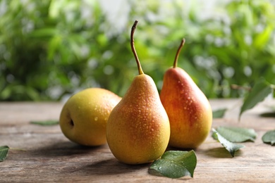 Photo of Ripe pears on wooden table against blurred background