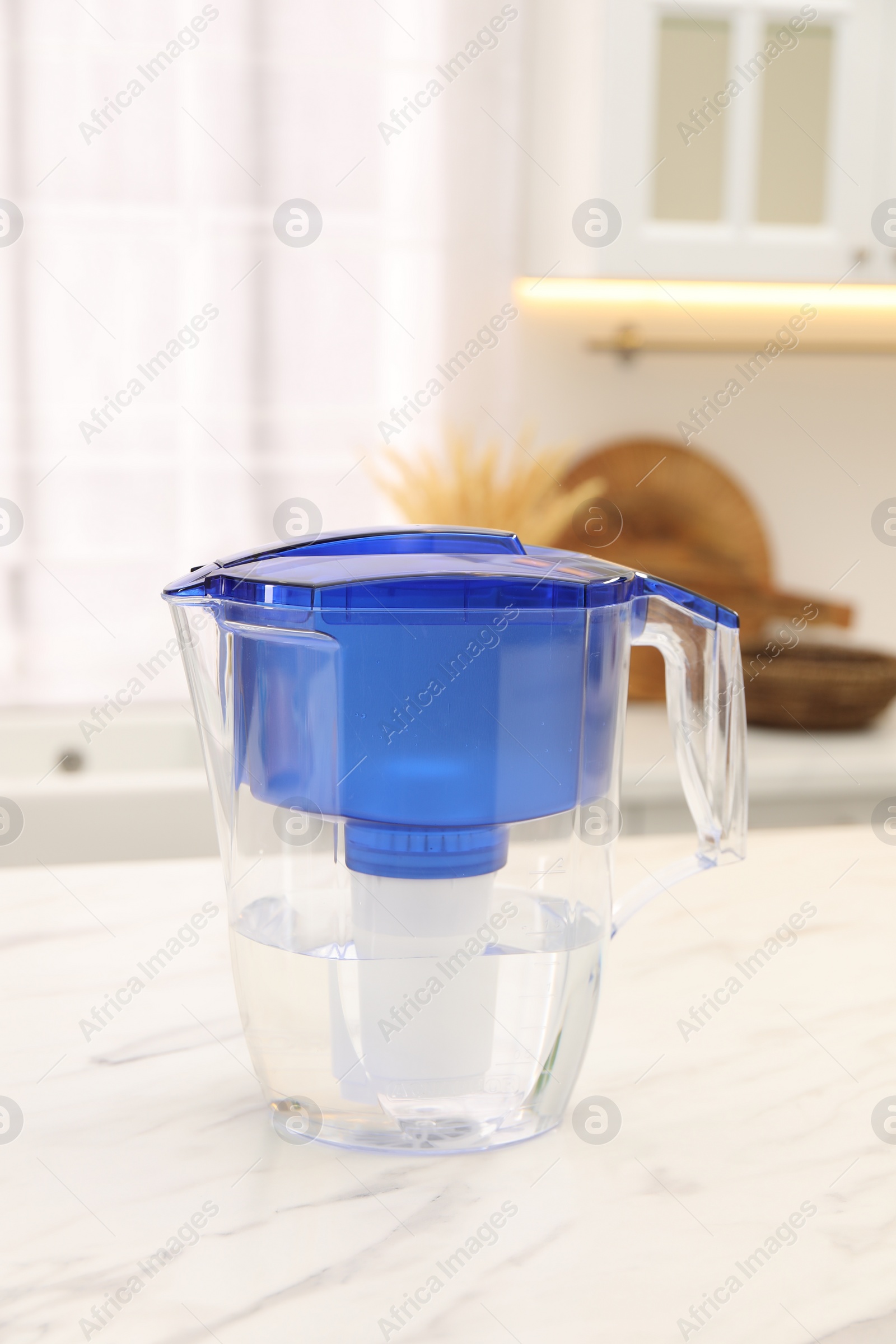 Photo of Water filter jug on white marble table in kitchen