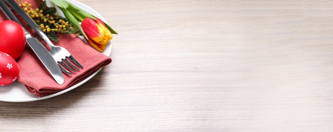 Festive Easter table setting with eggs on white wooden background, closeup. Space for text