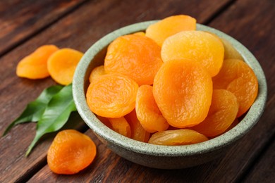 Photo of Bowl of tasty apricots on wooden table, closeup. Dried fruits