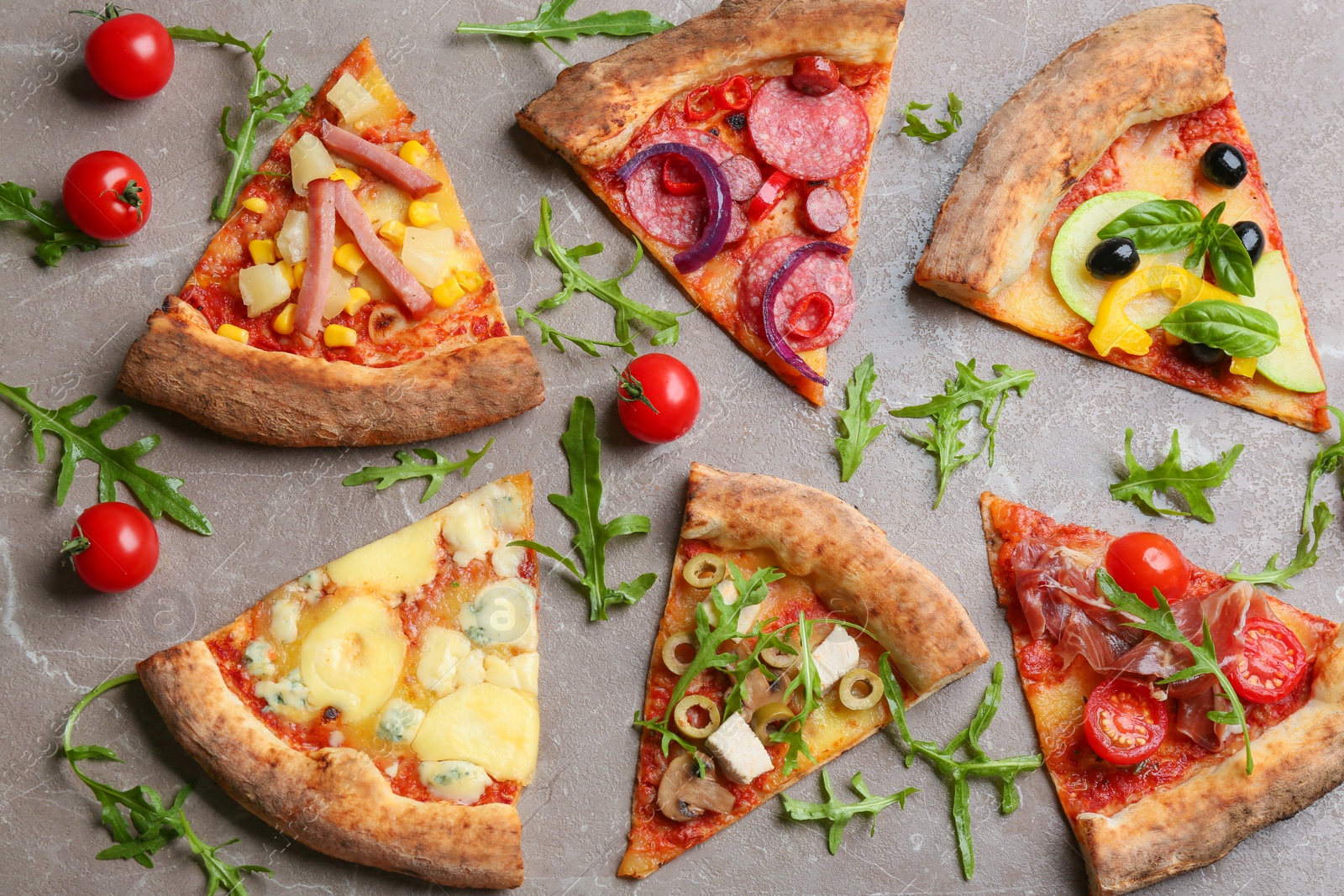 Photo of Flat lay composition with slices of different delicious pizzas on grey marble table