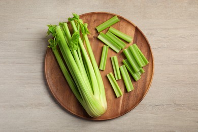 Photo of Board with fresh cut celery stalks and bunch on wooden table, top view