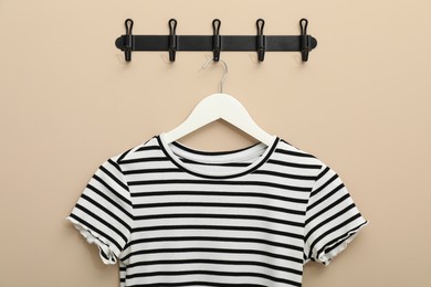 Photo of Hanger with striped t-shirt on beige wall