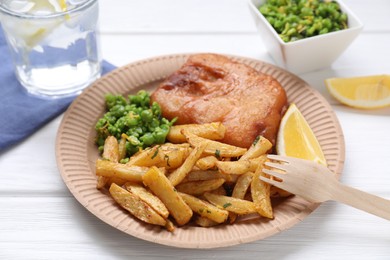 Photo of Tasty fish, chips, peas and lemon on white wooden table, closeup