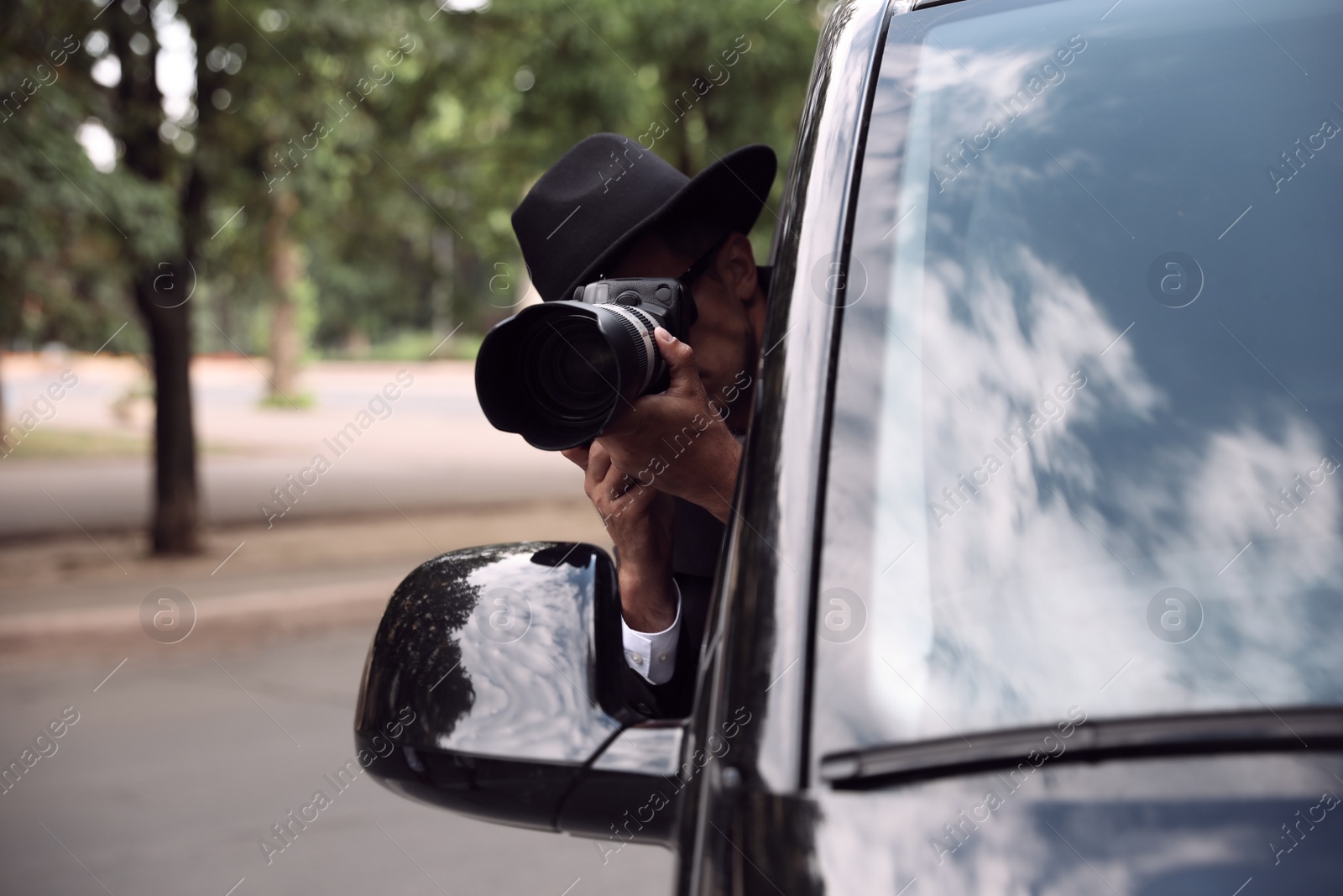 Photo of Private detective with camera spying from car