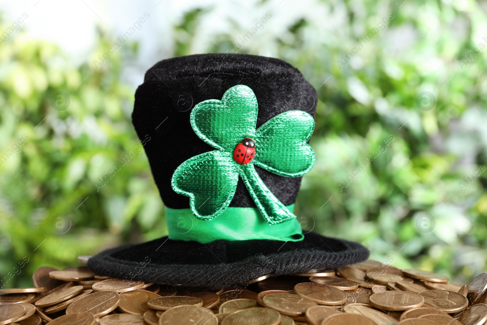 Photo of Black leprechaun hat with clover leaf on pile of gold coins. St Patrick's Day celebration