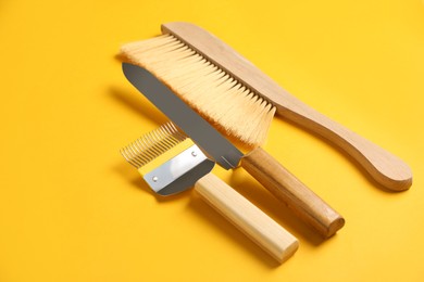 Photo of Three different beekeeping tools on yellow background