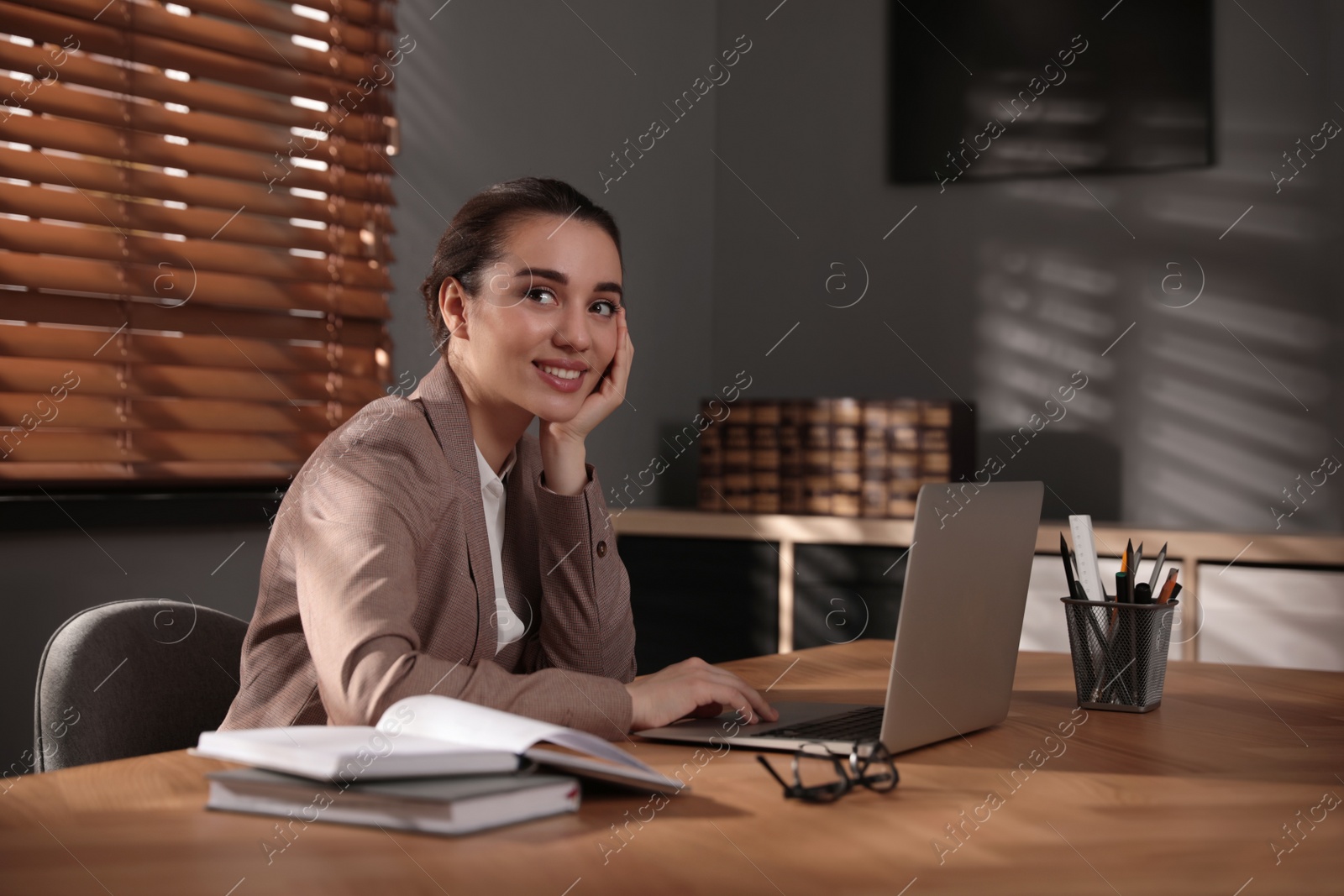 Photo of Woman working with laptop at wooden desk in office