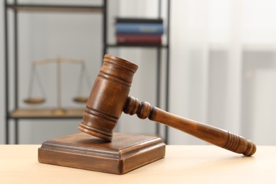 Photo of Wooden gavel and sound block on table indoors, closeup