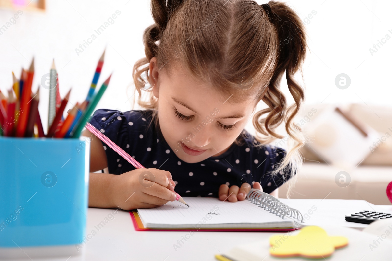 Photo of Cute little girl doing homework at table