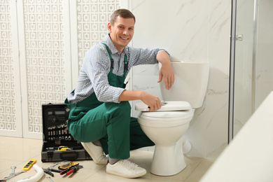 Professional plumber repairing toilet bowl in bathroom