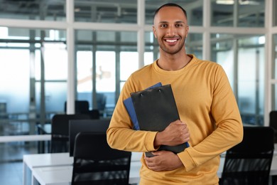 Photo of Happy man with clipboards in office, space for text