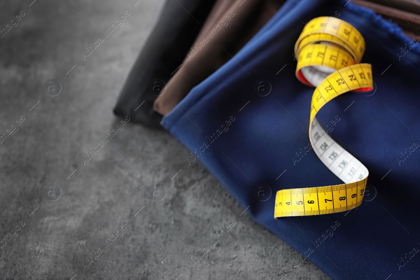 Photo of Fabrics and measuring tape for tailoring on grey background