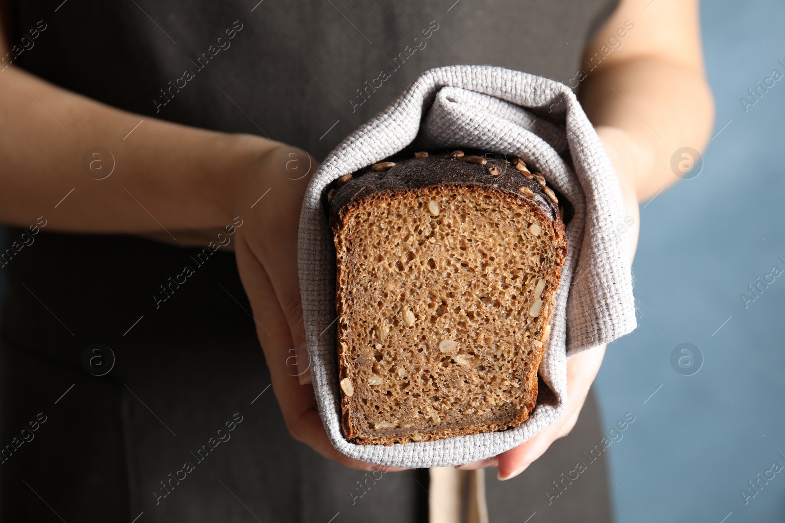 Photo of Baker holding cut bread on color background, closeup