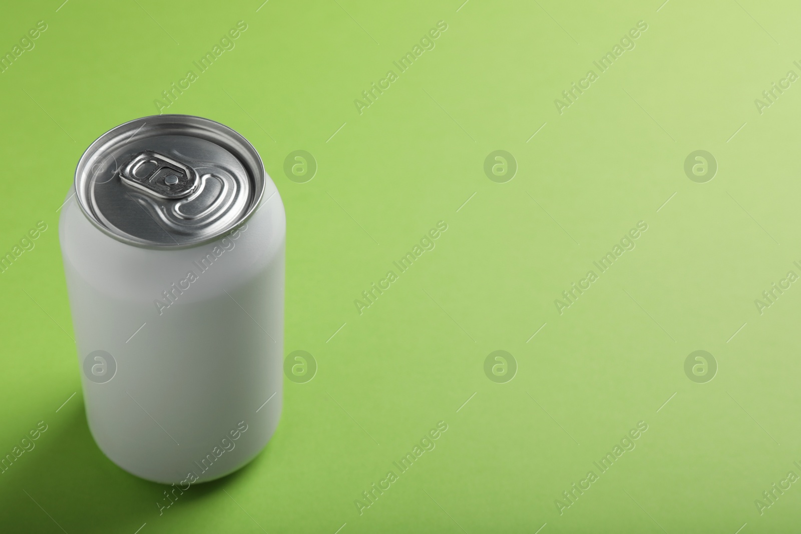 Photo of White can of energy drink on light green background. Space for text