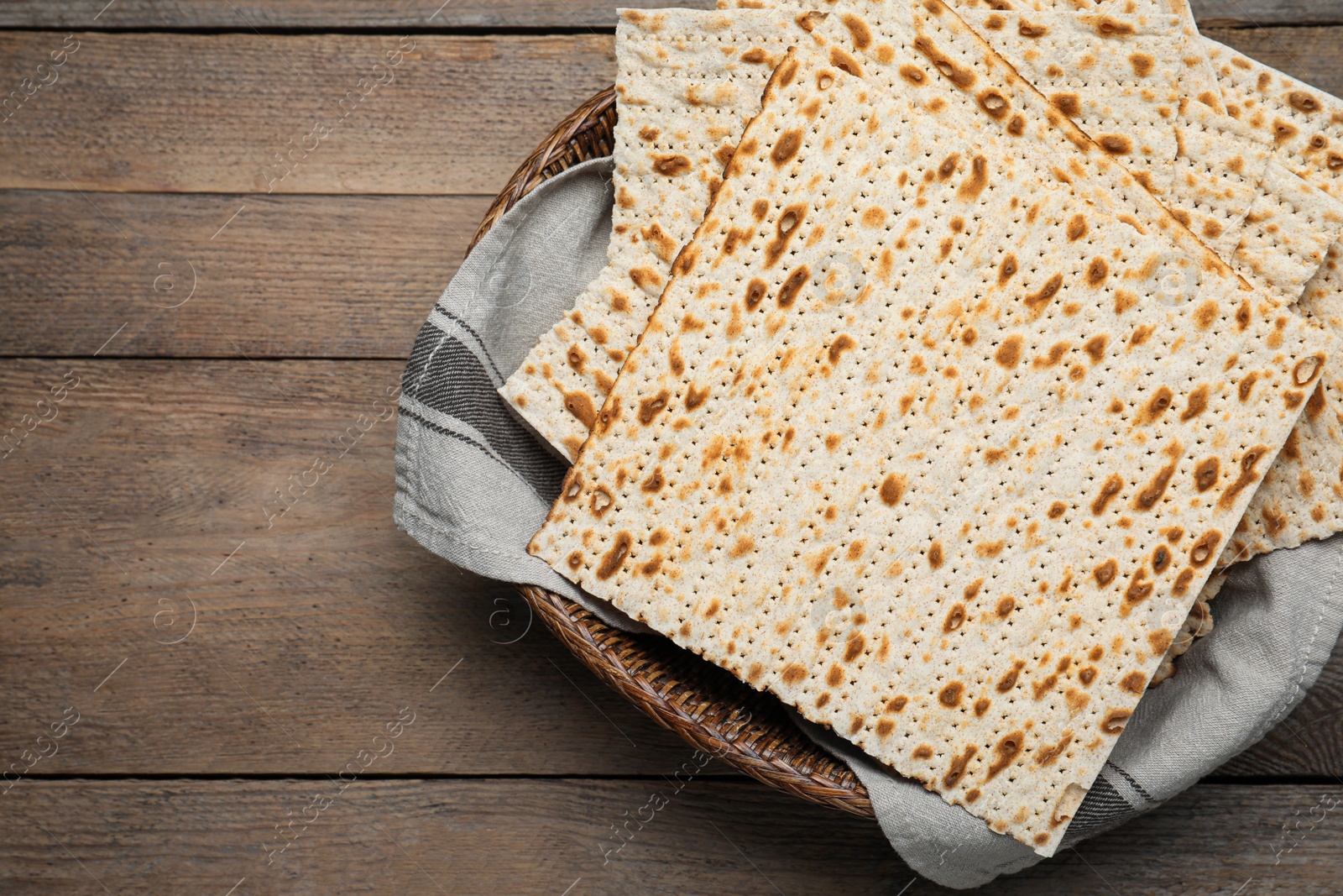 Photo of Traditional matzos in basket on wooden table, top view