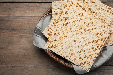 Photo of Traditional matzos in basket on wooden table, top view