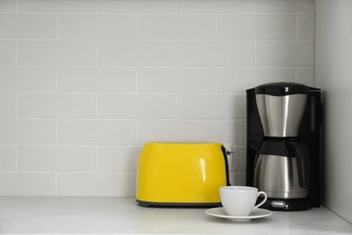 Photo of Modern yellow toaster and coffeemaker on countertop in kitchen. Space for text