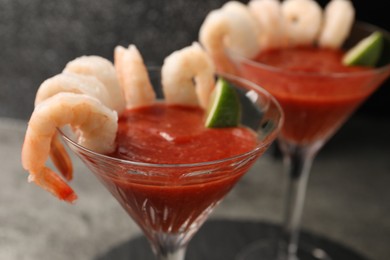 Photo of Tasty shrimp cocktail with sauce and lime in glasses on table, closeup