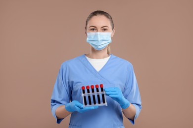 Photo of Laboratory testing. Doctor with blood samples in tubes on light brown background