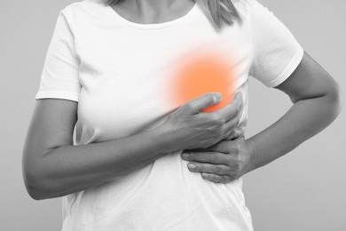 Image of Woman doing breast self-examination on grey background, closeup. Color accent effect