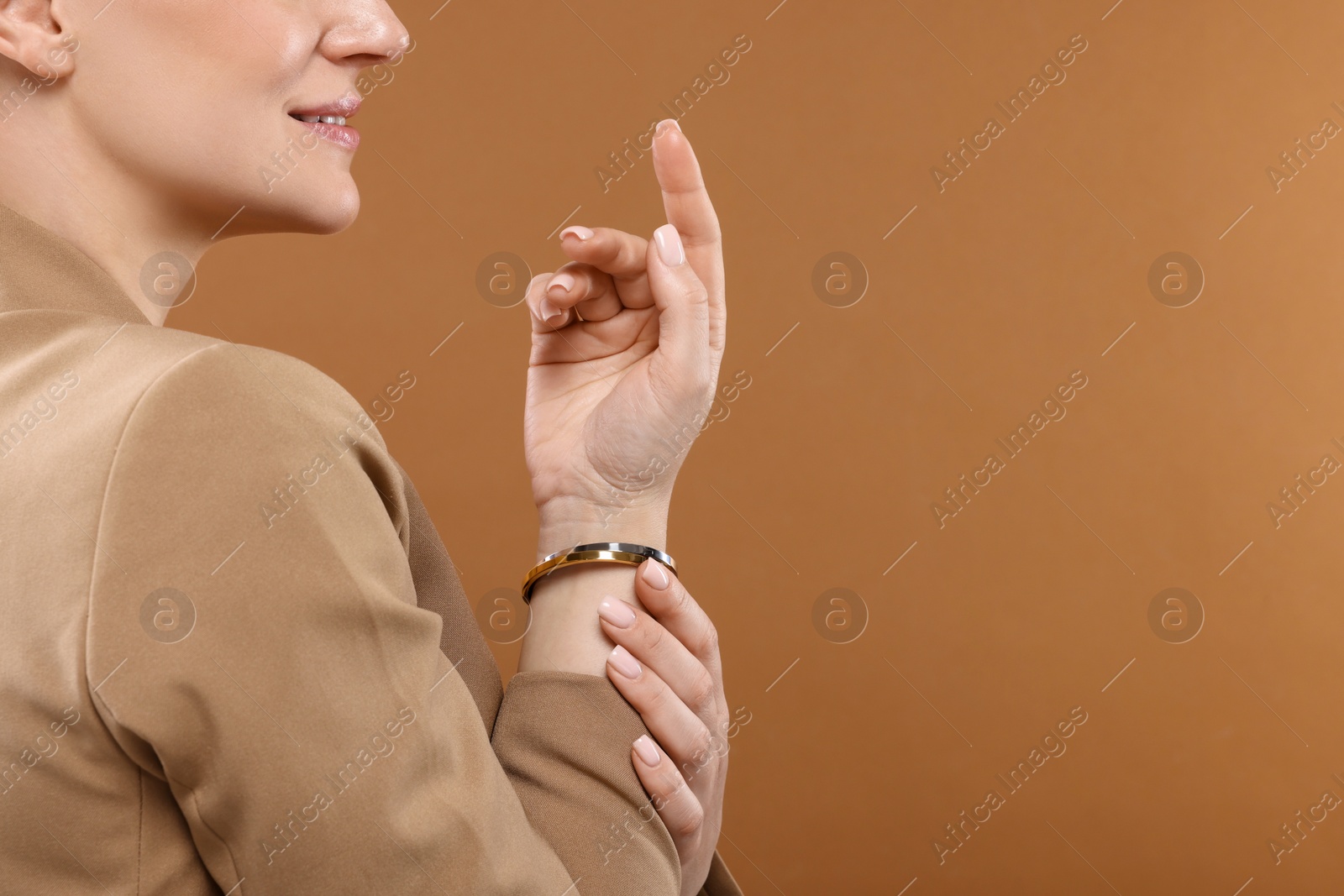 Photo of Woman with elegant bracelets on brown background, closeup. Space for text