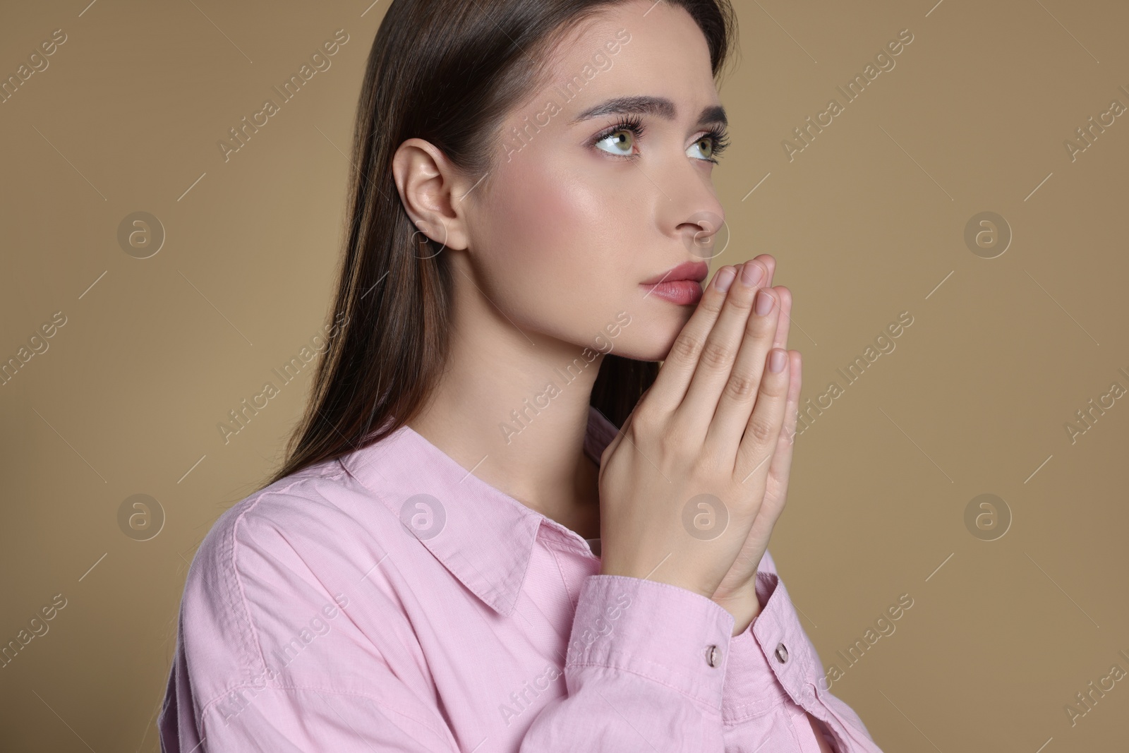 Photo of Woman with clasped hands praying on beige background