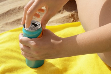 Photo of Woman opening aluminum can with beverage on yellow blanket, closeup