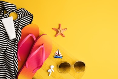 Photo of Flat lay composition with sunscreen and beach accessories on orange background, space for text