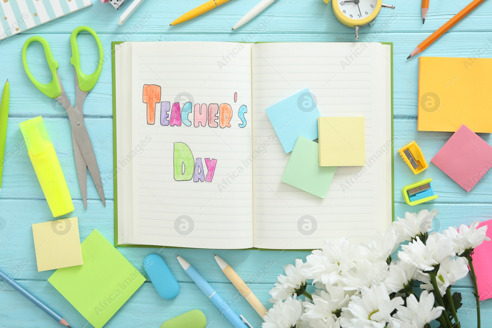 Photo of Flat lay composition with words TEACHER'S DAY, flowers and stationery on light blue wooden background