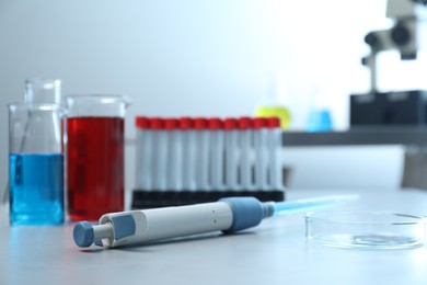 Laboratory analysis. Micropipette, beakers with liquids, petri dish and test tubes on grey table